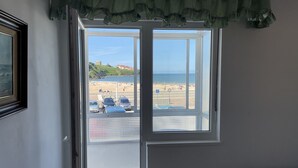 Una habitación con una ventana grande que da a la playa, una cama y una puerta.