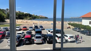 Un estacionamiento con varios autos y una playa al fondo.
