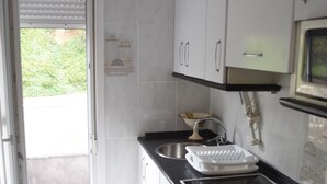 Una cocina con armarios blancos, encimera negra, un fregadero y una estufa.