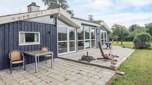 Et hus med en patio, et bord og stole, en træterrasse og en belægning af sten.