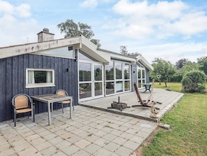 A house with a patio area featuring a table and chairs, a wooden deck, and a stone pathway. - 10 Person Holiday Home in Storvorde (Storvorde)