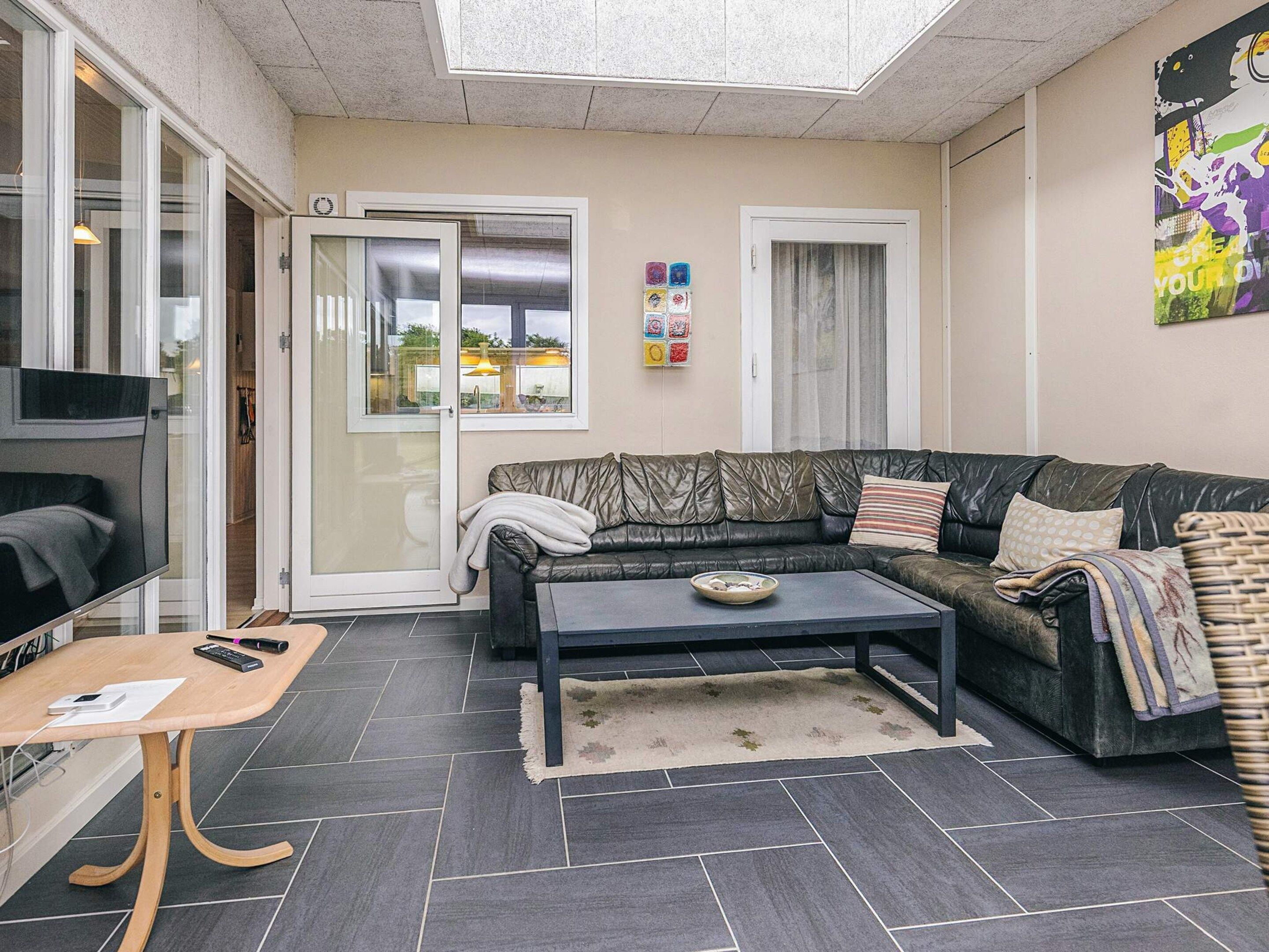 A modern living room with a leather sofa, a coffee table, and a TV on a wooden stand.