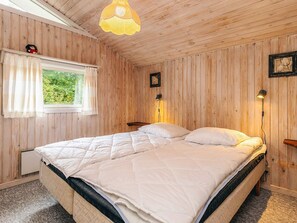 A wooden-paneled bedroom with a bed, a window with curtains, a hanging light fixture, and two wall-mounted lamps. - 10 Person Holiday Home in Storvorde (Storvorde)