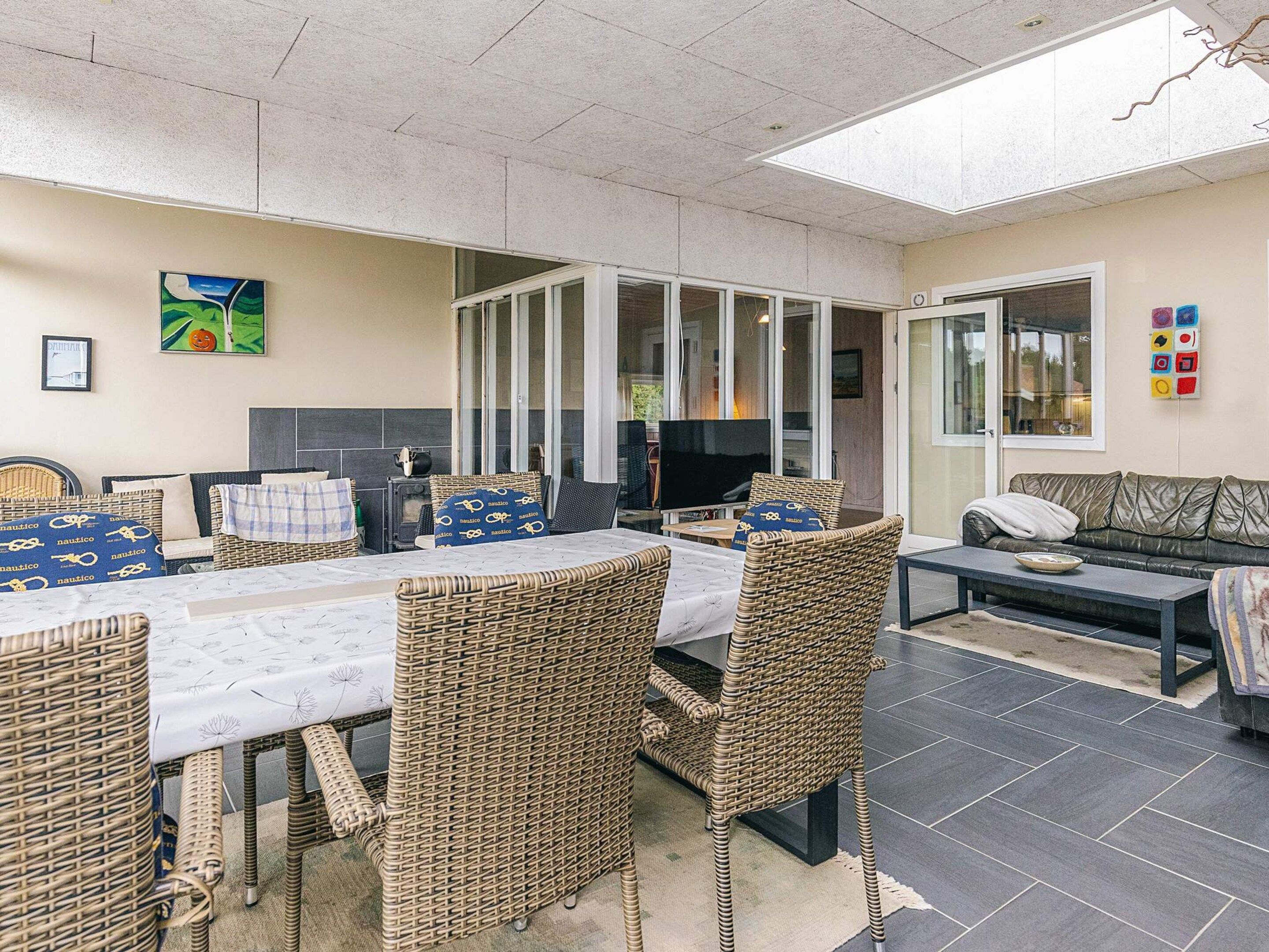 Un espace intérieur spacieux comprenant une table à manger, des chaises en osier, un canapé et un téléviseur.
