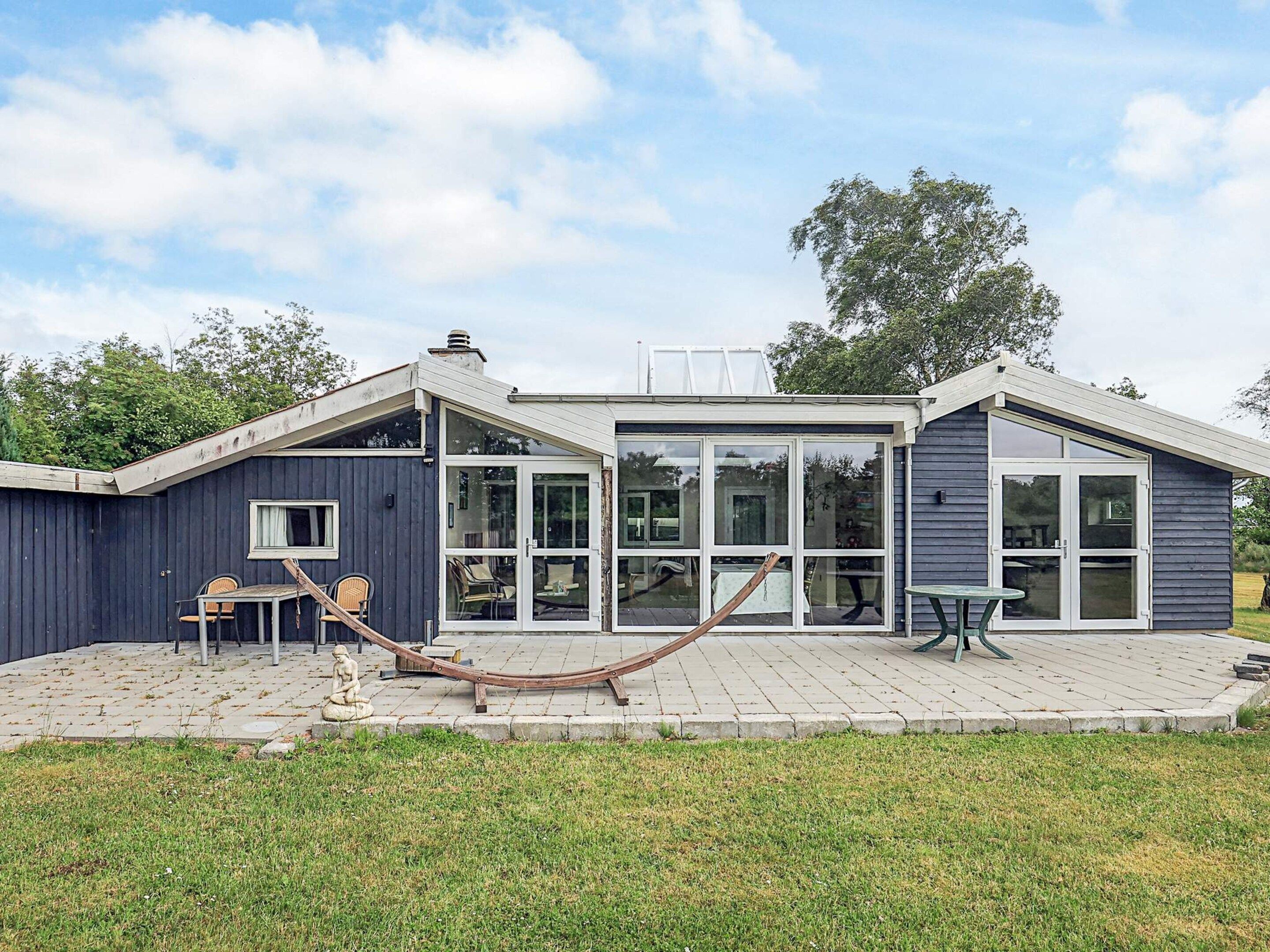 A modern house with a patio, large windows, and a hammock.
