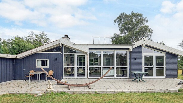 Et moderne hus med en terrasse, store vinduer og en hængekøje.