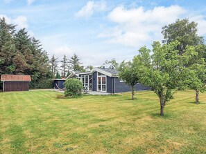 A modern house with a large front yard, a garage, and a tree.