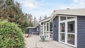 Et hus med terrasse, et bord og stole.