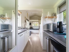A modern kitchen with stainless steel appliances, a central island, and a view to a living area.