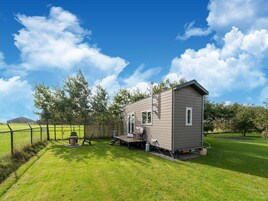 A small, single-story house with a porch, a fenced yard, and a clear blue sky.