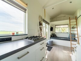A modern kitchen with a gas stove, white cabinets, and a window with a view of the countryside.