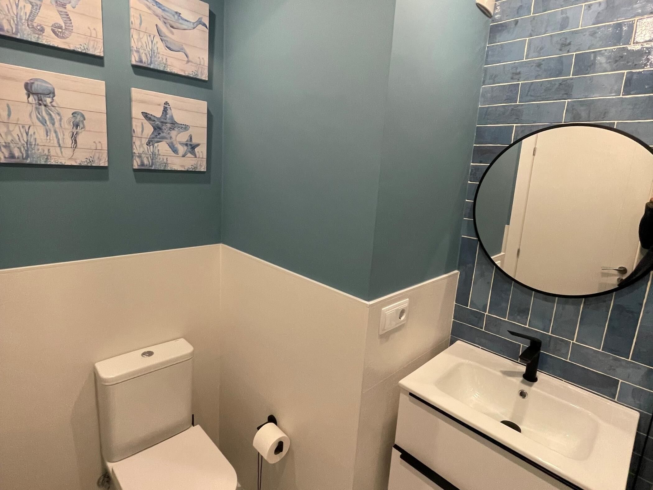 A bathroom with a toilet, sink, and a mirror.