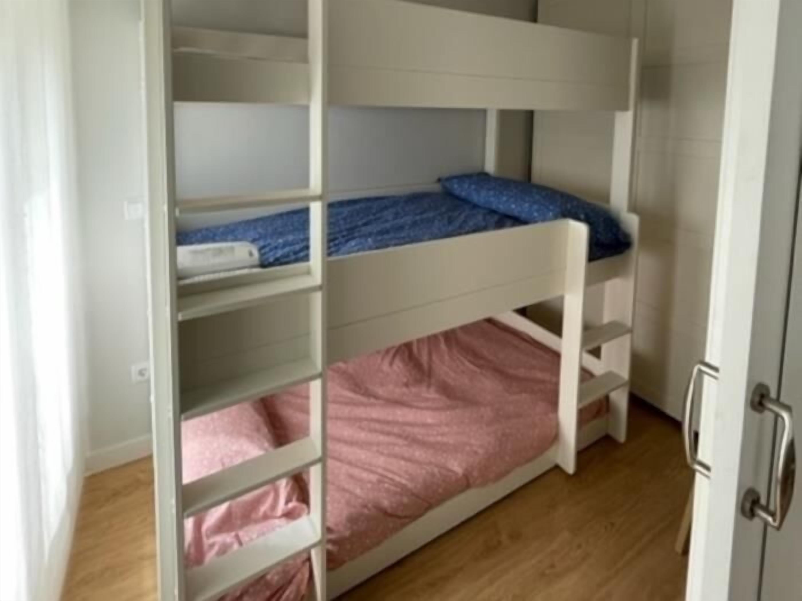 Une chambre avec un lit superposé, un matelas rose et une couverture bleue.