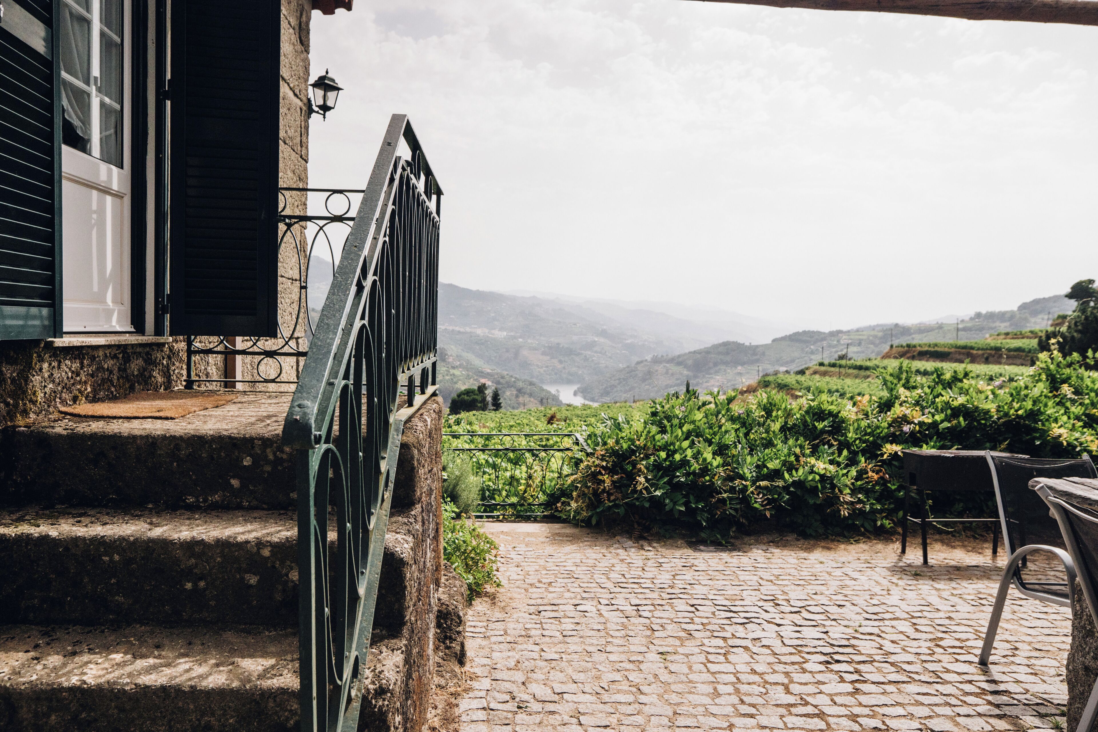 A stone staircase leading to a terrace with a view of rolling hills.
