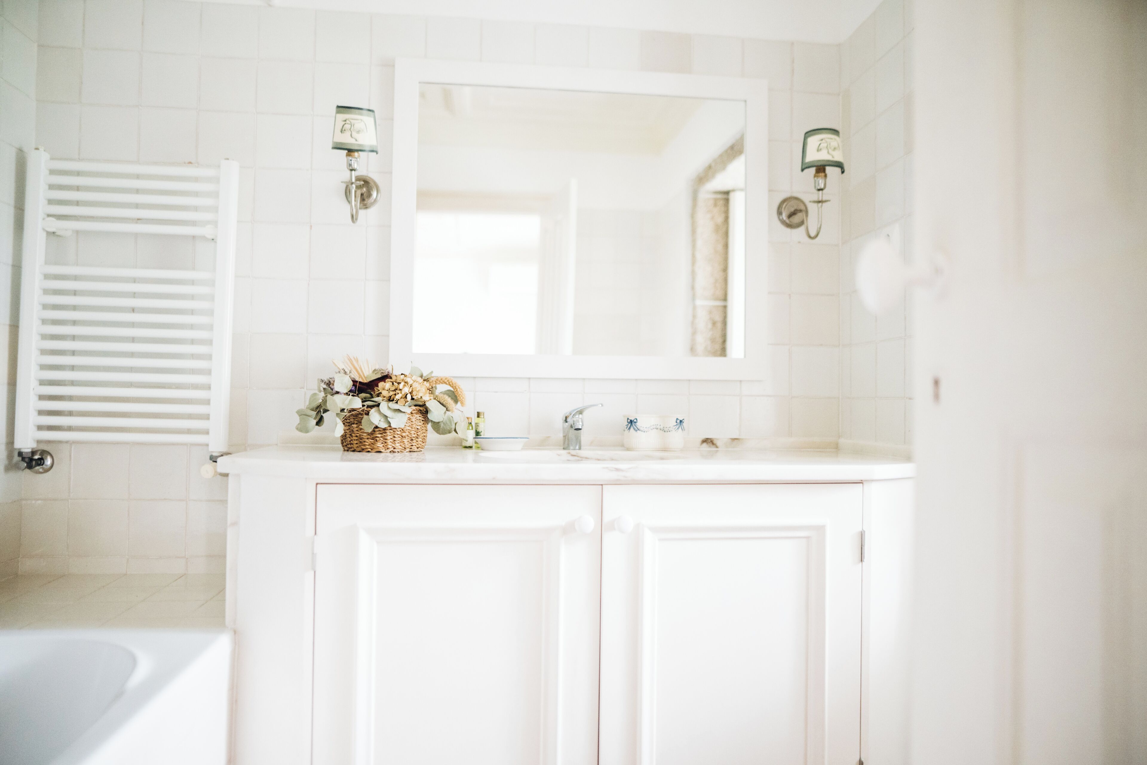 A bathroom with white cabinetry, a large mirror, and a bathtub.