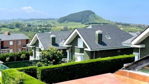 Un quartier résidentiel avec des maisons modernes, une pelouse bien entretenue et une colline qui se dessine à l’horizon.