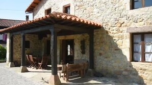 A stone building with a covered patio area featuring wooden furniture. - Spectacular house in Castaneda (Castaneda)