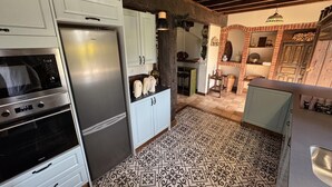 A kitchen with white cabinets, a stainless steel refrigerator, a built-in oven, and patterned floor tiles. - Spectacular house in Castaneda (Castaneda)