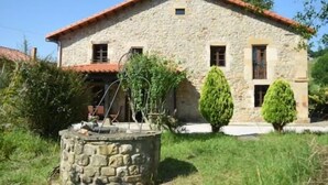 A stone house with a red-tiled roof, a small porch, and a stone well in the front yard. - Spectacular house in Castaneda (Castaneda)