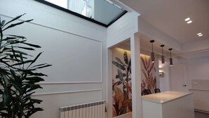 A modern kitchen with a central island, a radiator, and a large window with a view.
