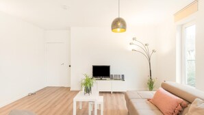 A modern living room with a sofa, a coffee table, a TV, and a decorative plant.