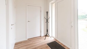 A hallway with a coat rack, a door, and a view of the outside.