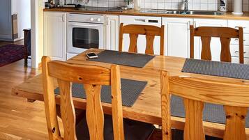 En matplats med ett träbord och stolar, ett kök i bakgrunden och en röd matta på golvet.