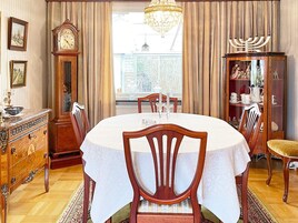Una sala da pranzo con un tavolo rotondo, sedie, un lampadario, un orologio e un candelabro.