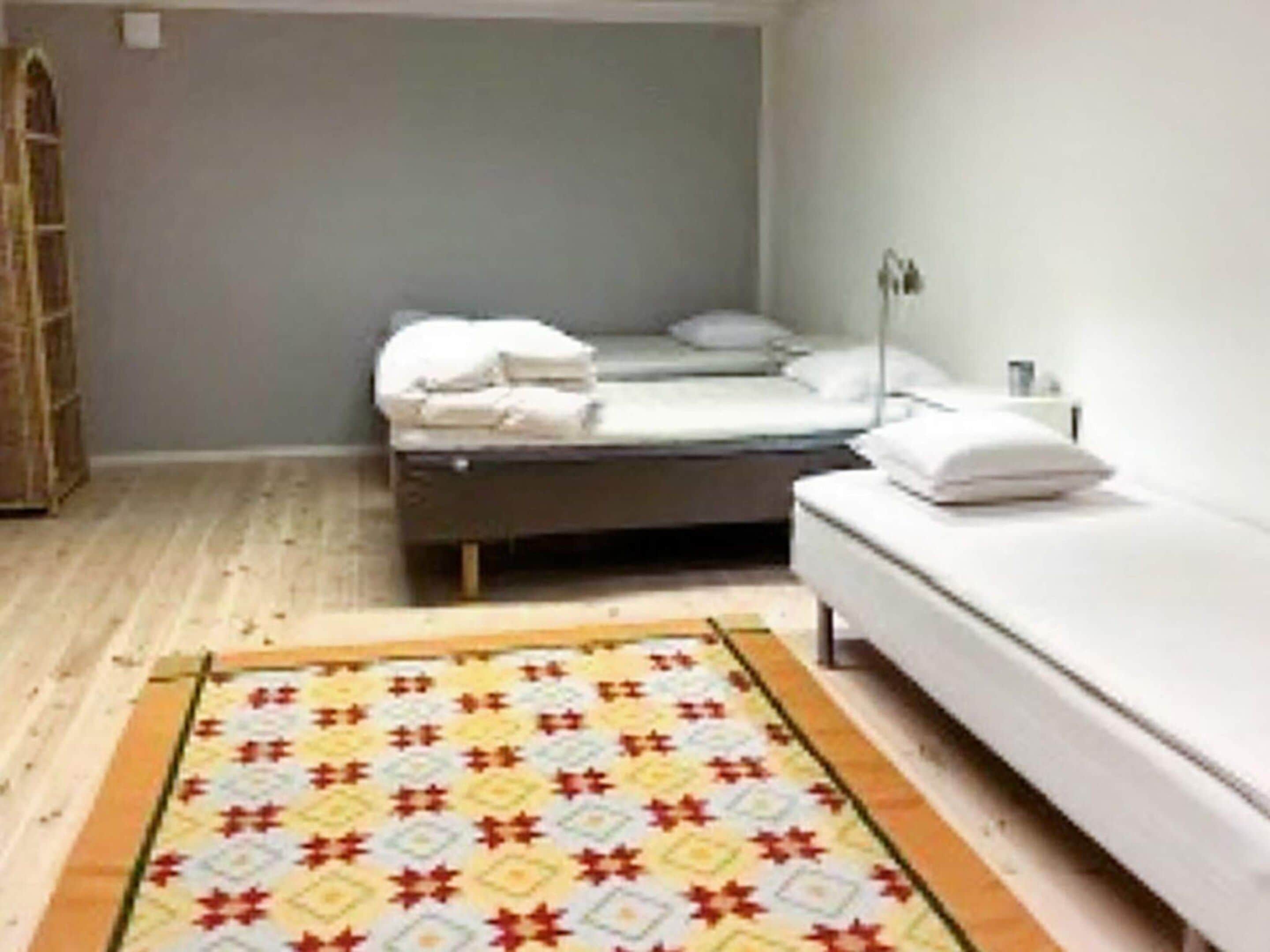 Una stanza con un letto, un comodino, una lampada e un tappeto decorato.