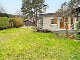 Un immobile residenziale con un prato curato, una casa in mattoni e un piccolo deposito.