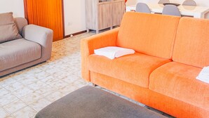 A living room with a sofa, a chair, a cabinet, and a dining area with a table and chairs.