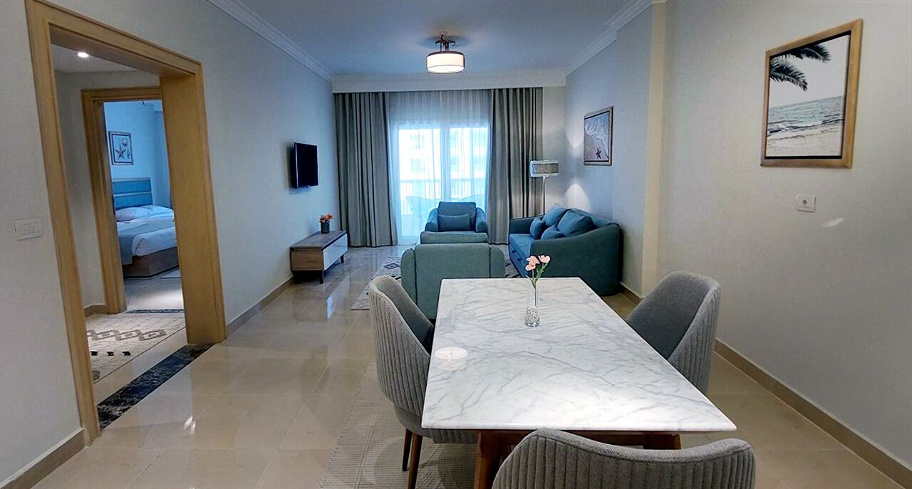 A modern living room with a dining table, sofas, and a TV.
