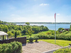 A lakeside property with a flagpole, a wooden deck, and a view of the lake. - 5 Star Holiday Home in Kolding (Kolding)