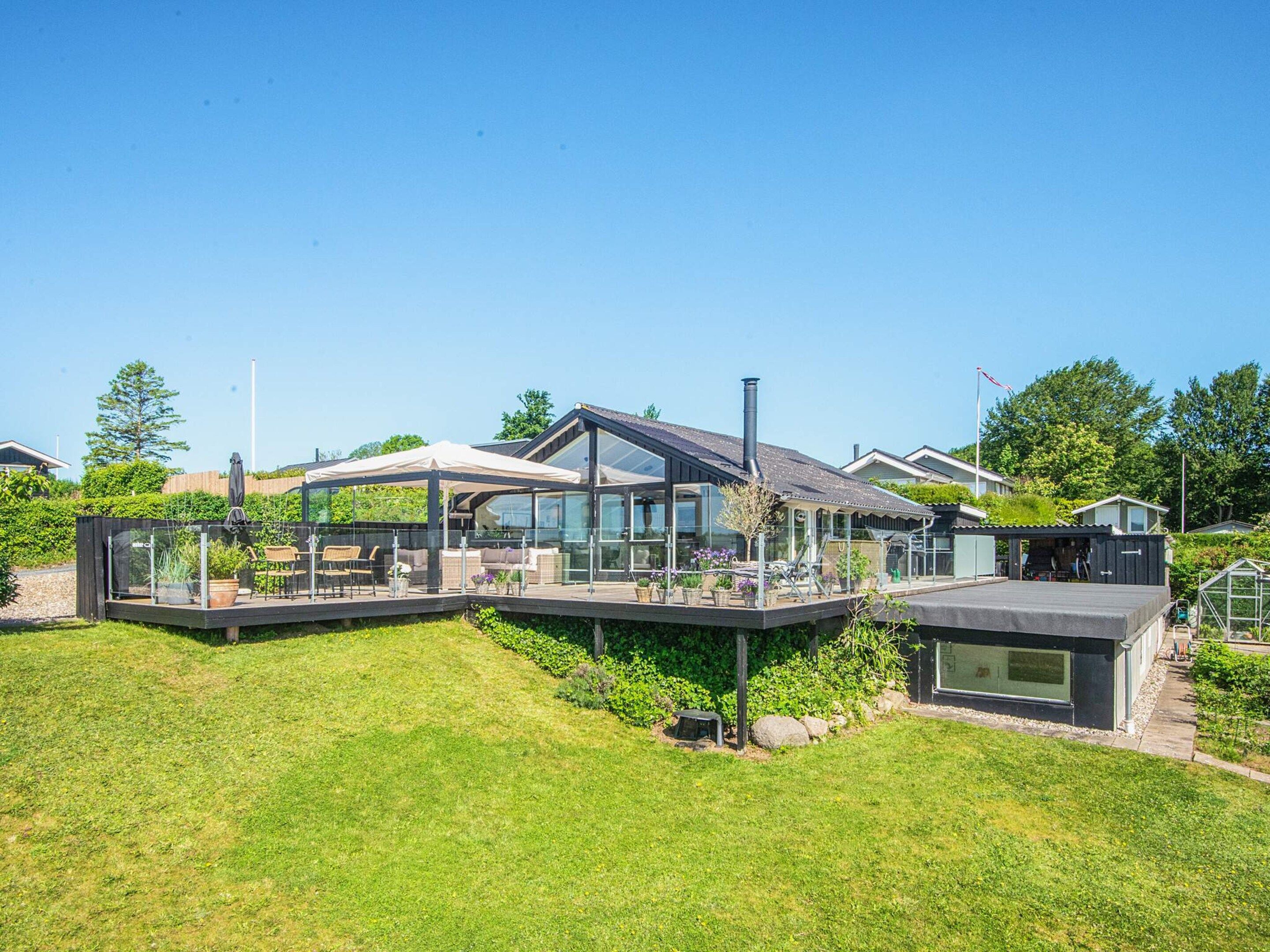 A modern house with a glass conservatory, a deck, and a chimney.