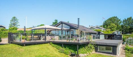A modern house with a glass conservatory, a deck, and a chimney.