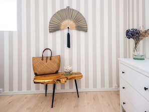 A room with a striped wall, a wooden table with a woven bag, a glass vase with flowers, and a white dresser. - 5 Star Holiday Home in Kolding (Kolding)