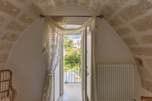 A narrow hallway with a white radiator, a wicker chair, and a view of a balcony with red flowers. - 3906 Corte Degli Aranci by Barbarhouse (Fasano)