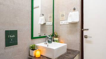 A bathroom with a white sink, green-framed mirror, and a sign that says "Flush".
