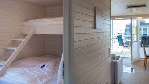 A room with a bunk bed, a wooden wall, and a view of the outside. - ISA Comfortable Holiday Residence (Grossenbrode)