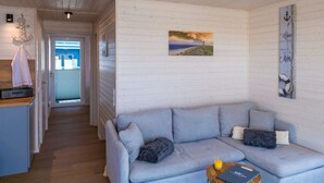 A cozy living area with a sofa, a small table, and a painting on the wall. - ISA Comfortable Holiday Residence (Grossenbrode)