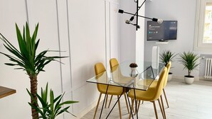 A modern dining area with a glass table, yellow chairs, and a black chandelier. - NEW Gorgeous Central Apartment - Beachfront - 3 BD (SAN SEBASTIAN)