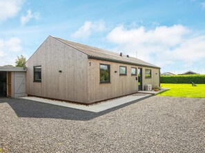 A modern single-story building with a sloped roof, large windows, and a gravel driveway. - 8 Person Holiday Home in Hejls (Hejls)