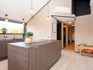 Une cuisine moderne avec un îlot central, des murs en bois et des luminaires suspendus.