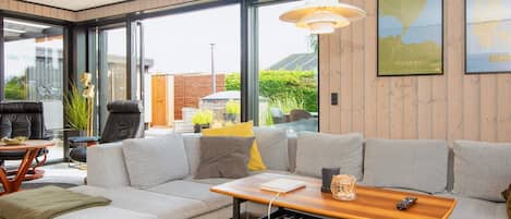 A modern living room with a sofa, coffee table, and a view through large windows.