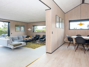 A modern living room with a sofa, chairs, a dining table, and a large window. - 8 Person Holiday Home in Hejls (Hejls)