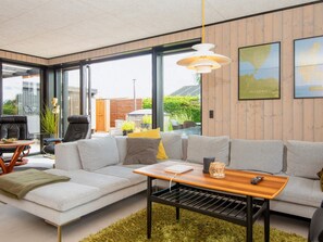 A modern living room with a sofa, coffee table, and a view through large windows.