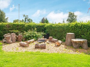 Un jardin avec un espace de repos circulaire, entouré de souches d’arbres et de troncs.