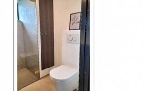 A small bathroom with a toilet, a shower, and a towel rack.