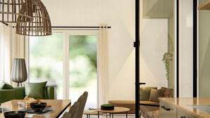 A modern dining area with a wooden table, chairs, and a small round table with a bowl. There is a sofa and a plant in the background. - Chalet in Veluwe With Peaceful Surroundings (Voorthuizen)