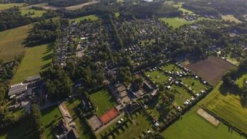 Luchtbeeld van een woongebied met huizen, groenstroken en een groot open veld.